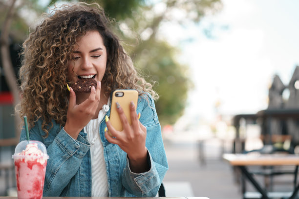 一名坐在咖啡店里使用手机的拉丁妇女。图片下载