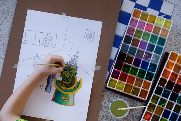 孩子的手在纸上画艺术画，用两个水彩托盘在白色大理石桌上图片下载