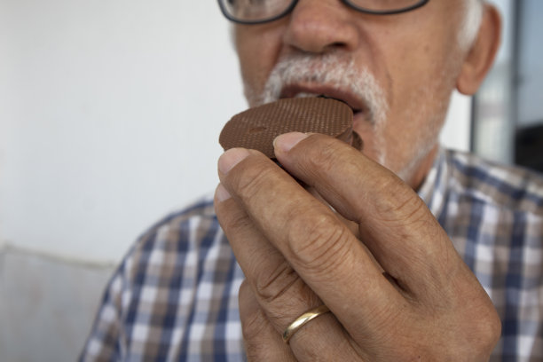 老人在吃巧克力饼干。享受退休生活的概念图片下载