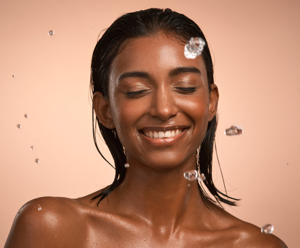 一个年轻漂亮的女人在做她的日常皮肤护理在棕色的背景下图片下载