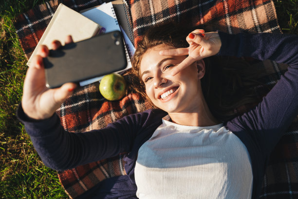 快乐的年轻人躺在公园的毯子上图片下载