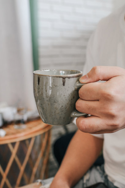 一个拿着陶瓷水杯的人。手捧一杯纯净水。喝健康饮料的男人图片下载