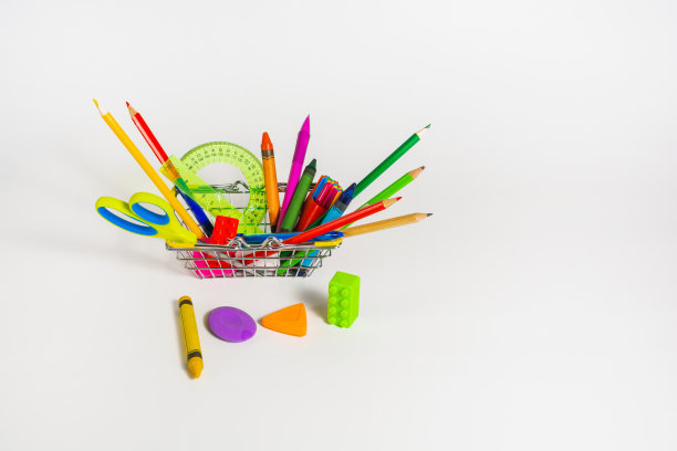 学校用品和文具放在一个篮子里，背景是白色的。孤立的图片下载