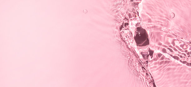 时尚夏季自然背景：粉色液体着色清澈水面纹理，带飞溅气泡和文案空间，阳光下失焦水波图片下载