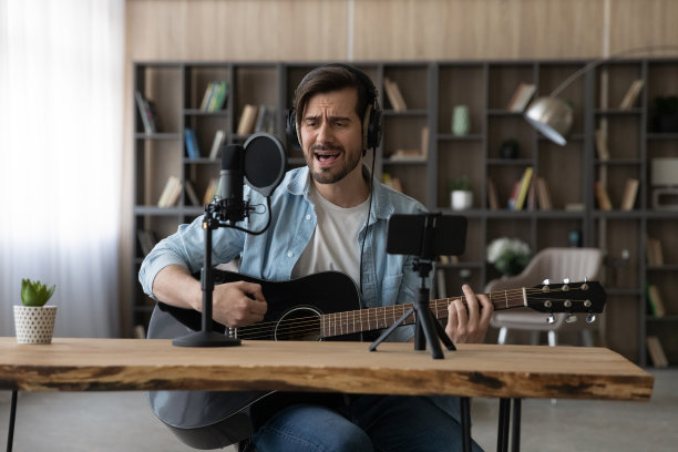 快乐年轻的灵感男子弹吉他，录制自己的歌曲。图片下载