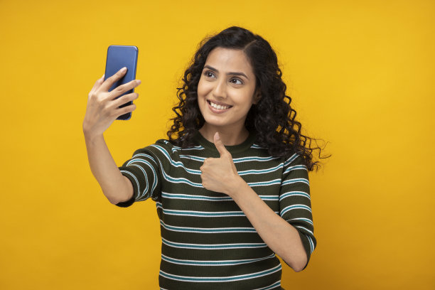 一名年轻女子孤立地站在黄色背景下自拍图片下载