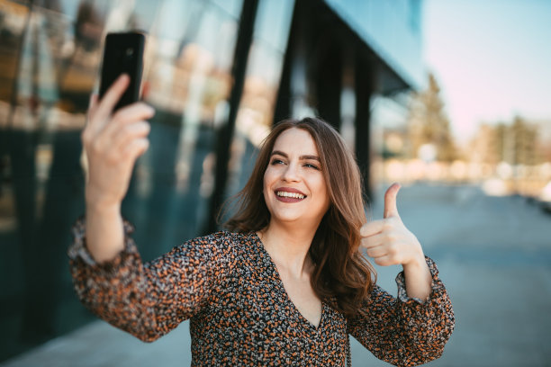 时尚女性在现代办公大楼前自拍图片下载