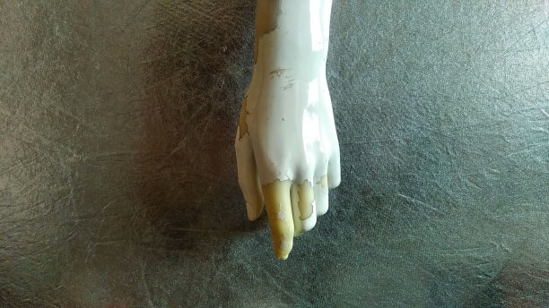 古老和风化的女性的瓷器手与损坏的手指人体模型，在一个黑暗的平面背景图片下载