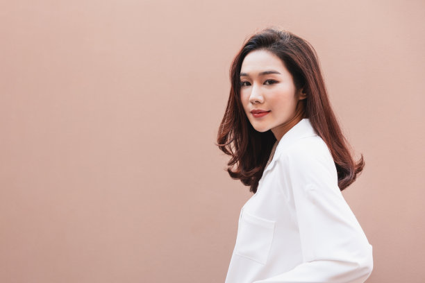 年轻的亚洲女人摆出时髦的样子。肖像一个微笑的黑发女人自然化妆穿时装衣服。漂亮的女模特穿着一件白色的大衬衫。人美丽的概念。图片下载