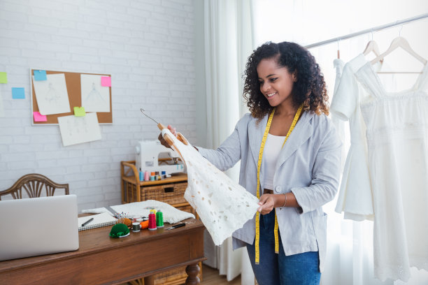 美丽微笑的肖像非洲裔美国黑人女设计师工作与电脑在裁缝织物时装小商车间。年轻业主企业家创意女孩纺织经营理念图片下载