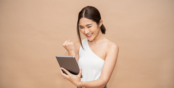 美丽的亚洲成功商业女孩的肖像庆祝与智能手机的复制空间在白色的背景。成功快乐女性教育互联网科技创业的经营理念图片下载