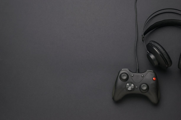 耳机和黑色背景的游戏机。平的。文本。图片下载