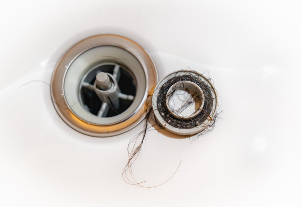 一张头发掉在浴缸排水管里的照片。水周围的麻烦。堵塞的水。图片下载