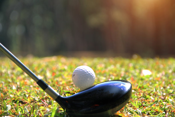 高尔夫球杆和高尔夫球靠近草地与日落。图片下载