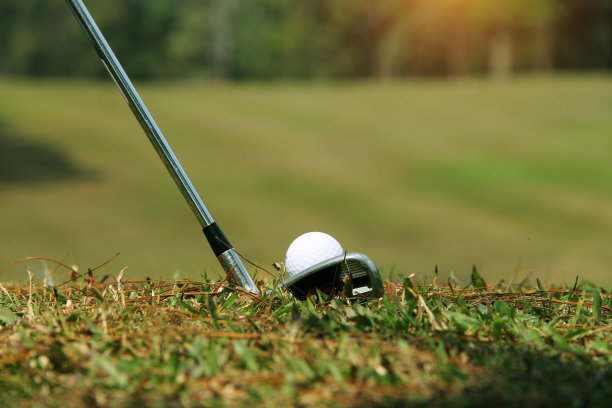 高尔夫球杆和高尔夫球靠近草地与日落。图片下载