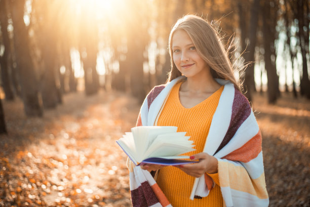 一个小女孩在秋天公园看书的照片图片下载