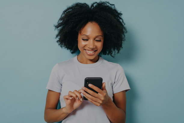 漂亮的卷发女人拿着现代的手机，在智能手机上打字图片下载