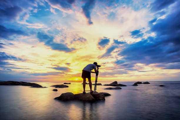 一个摄影师的剪影，在日落时有水的反射光的美丽时刻。图片下载