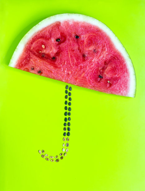 绿黄色背景下的西瓜片和种子做成的雨伞图片下载