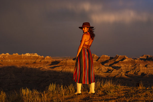 黄昏时分，美丽的女子站在沙漠峡谷前的金光下图片下载