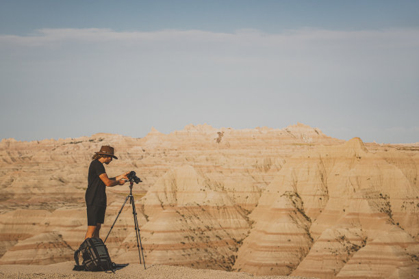 一名男子在沙漠荒地上拍摄崎岖的地形图片下载