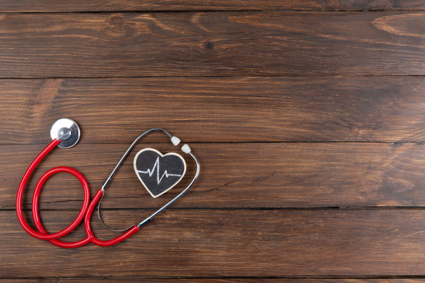 医生的工作场所。木桌背景上的听诊器和小心脏图片下载