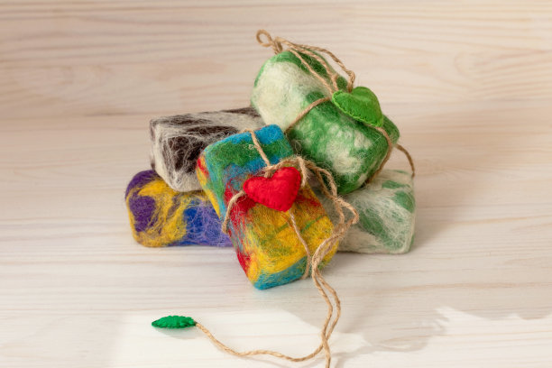 天然手工肥皂在彩色羊毛与红色的心在轻的自然木制背景。剥离毛巾的概念。自我关爱，承诺环保产品。图片下载