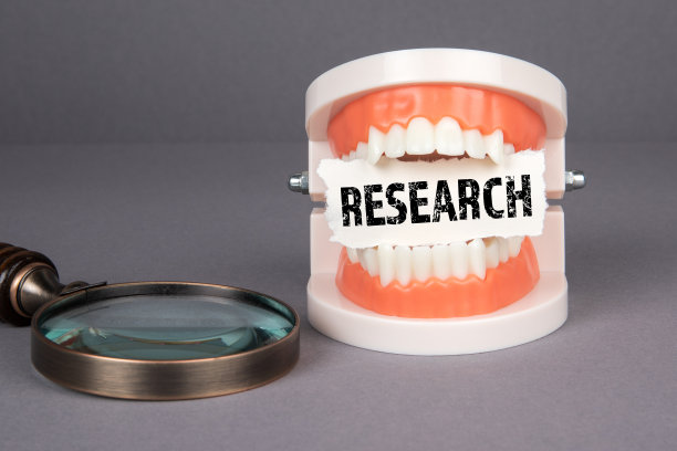 研究。牙齿模型和放大镜上的灰色背景图片下载