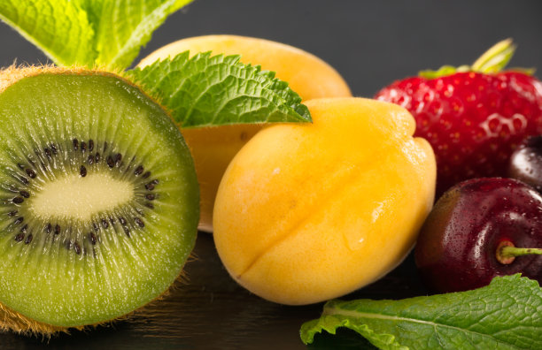 一张静物照片，新鲜成熟的水果用薄荷叶装饰在黑暗的背景和在潮湿的桌子上的倒影。天然产品，收获，营养，饮食和室内艺术装饰。图片下载