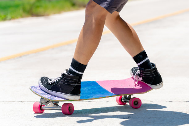 在一个阳光明媚的日子里，一个年轻的亚洲男子正在乡村小路上玩滑板。玩冲浪图片下载