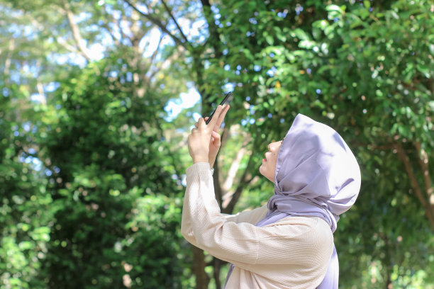 亚洲年轻女性在公园里用手机拍照片发到社交媒体上图片下载