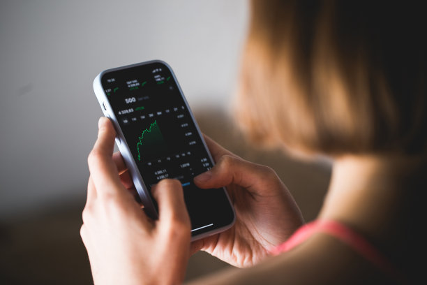 年轻女性投资者手持一款手机投资应用指数成长图图片下载