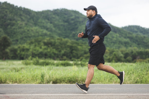 亚洲男子穿着运动服在山路上跑步。年轻人在大自然中慢跑锻炼身体。健康的生活方式和运动理念图片下载