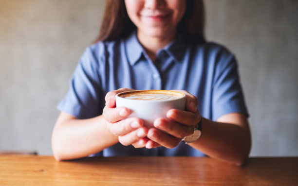 一个女人拿着一杯热咖啡给人看图片下载