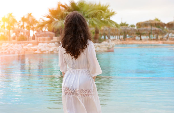 美丽的女孩在一个豪华的热带游泳池与棕榈树的背景。豪华的酒店。暑假的概念图片下载