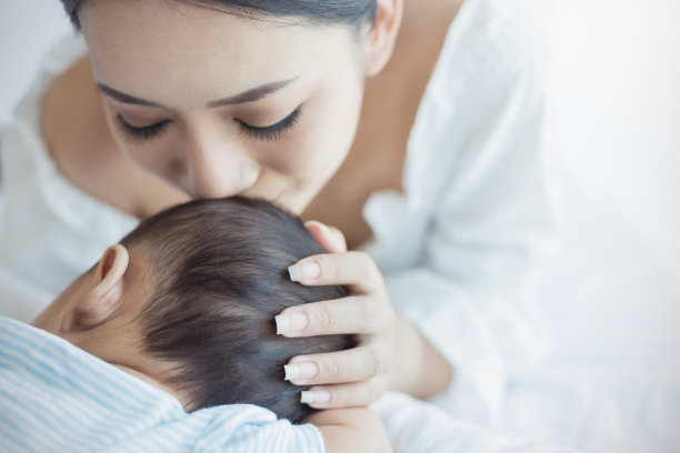 特写照片，美丽的年轻亚洲母亲亲吻她刚出生的婴儿睡在医院的床上。医疗保健家庭爱的生活方式母乳喂养幼儿园motherâ的日子概念图片下载