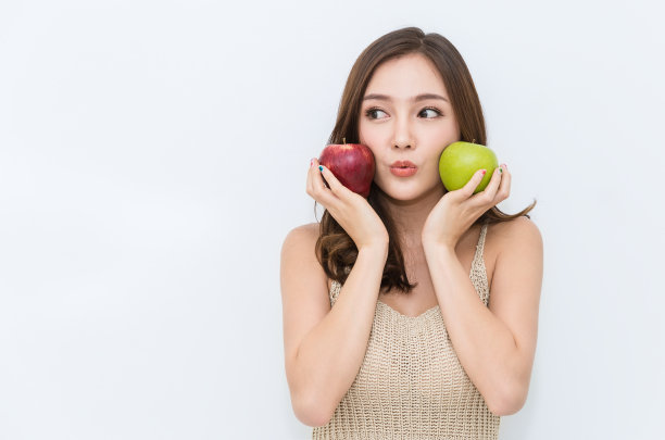 年轻美丽性感的亚洲女孩的肖像，手握绿苹果和红苹果，使她强壮和健康，素食女性孤立在白色的背景保健和医疗理念。图片下载