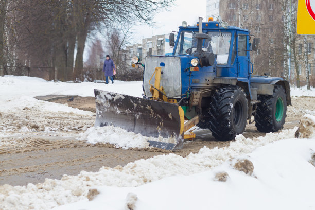 拖拉机冬天在路上用铲斗铲雪图片下载