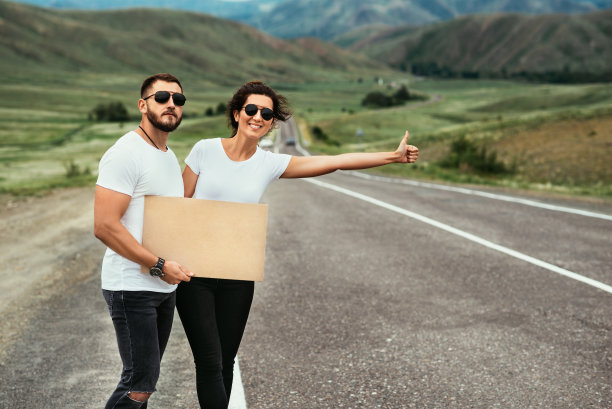 一个男人和一个女人在搭便车。漫游癖，自动停车的旅行理念。年轻人搭便车旅行。在路上搭便车的夫妇。搭便车旅行。汽车旅行。两个在路边。本空间图片下载