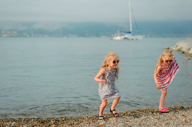 两个小女孩在海边的卵石滩上鬼混图片下载