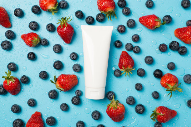 头顶照片的浆果草莓蓝莓到处是水滴和白色管奶油孤立在蓝色背景图片下载