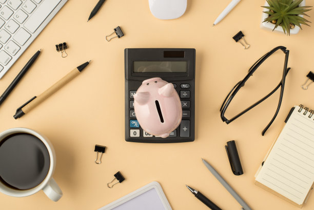 在孤立的米色背景上的键盘鼠标植物笔、夹子、咖啡杯、存钱罐和笔记本的顶部视图照片图片下载