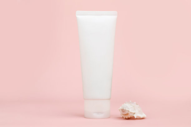 前视图无品牌白色挤瓶奶油管和贝壳在粉红色的背景。含钙和海盐的化妆品。模型,模板,特写镜头。图片下载
