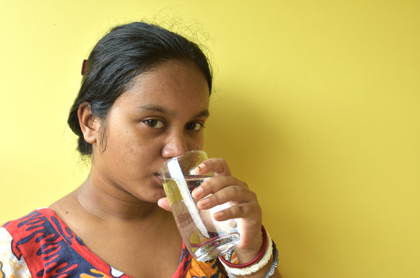 一幅年轻女子在家中喝水的画像。选择性聚焦与复制空间。图片下载