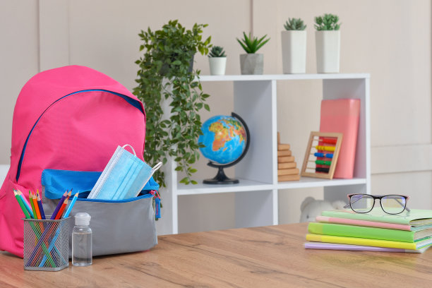 背包里有学习用品、消毒剂和医用防护口罩。在冠状病毒后回到学校和幼儿园。开学季的开始。安全学习。图片下载
