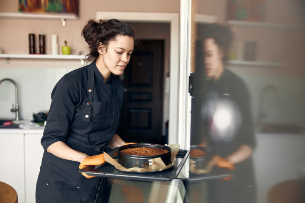 年轻的职业女厨师正在她的轻现代厨房里准备美味的蛋糕图片下载