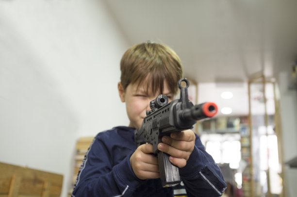 小男孩在玩突击步枪。玩具枪的概念图片下载
