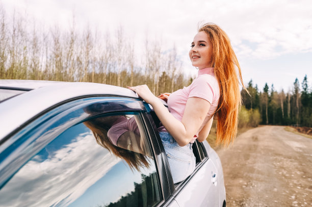 快乐的年轻红发女人从车窗里图片下载
