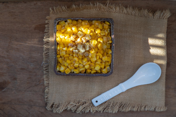 将甜玉米与黄油及调味料一起炒熟，在陶碗和陶勺中撒上黑胡椒末。图片下载
