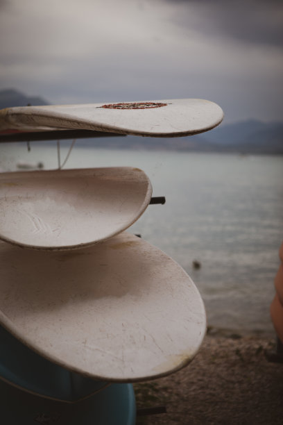 一些不同的冲浪板相互堆叠在湖岸边图片下载